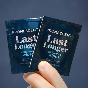 Person holding two Promescent desensitizing wipes for premature ejaculation