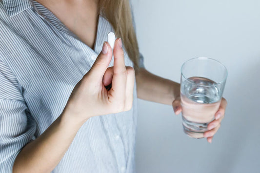 Woman holding rae in the mood pill and a glass of water
