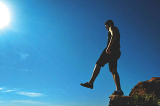 man standing on cliff edge with foot out in front of him