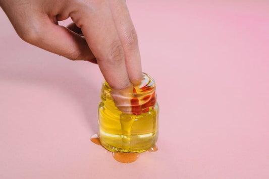 Woman's fist two fingers being dipped into a container of sexual lubricant