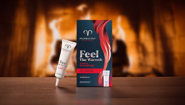 Promescent warming female arousal gel and product box on a wooden table in front of a fireplace